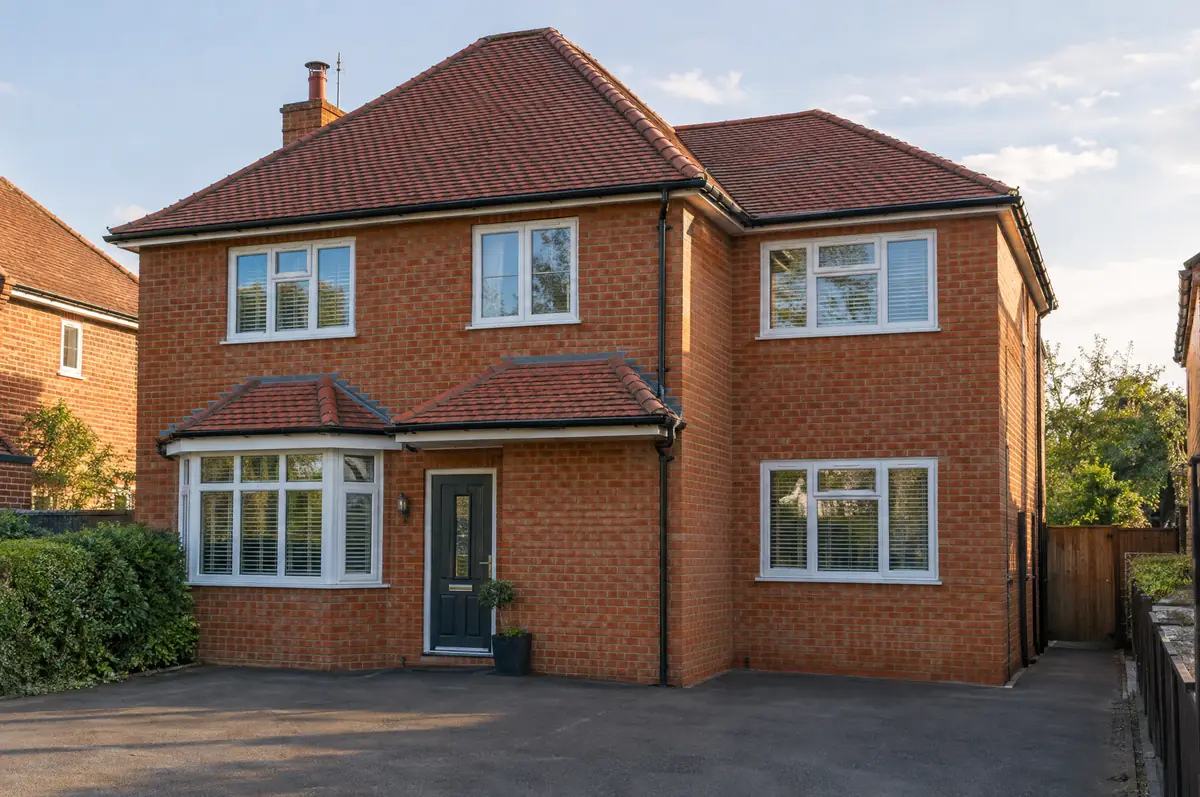 Detached brick house with a new two-storey side extension and matching hipped roof