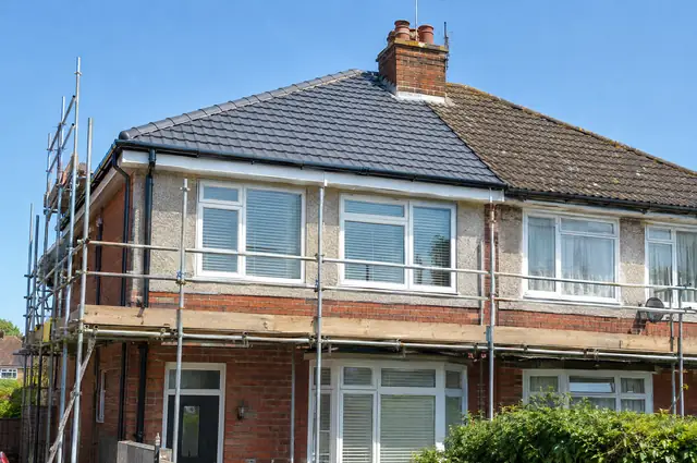 Semi-detached house with scaffolding and a newly re-tiled roof with dry ridge