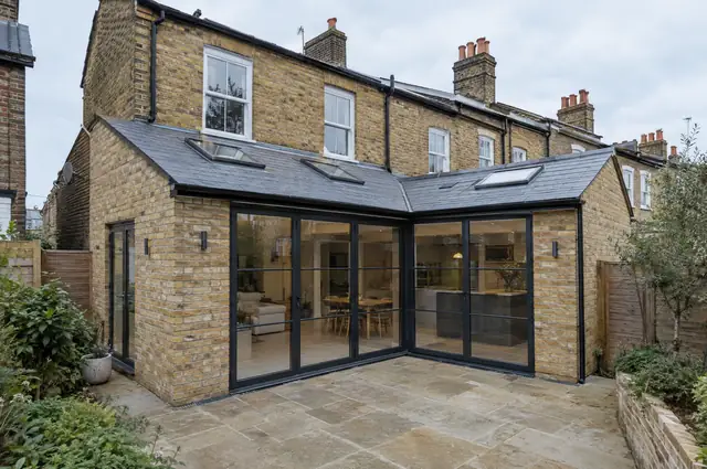 L-shaped wraparound extension with slate roof, rooflights and black glazed doors on a terrace